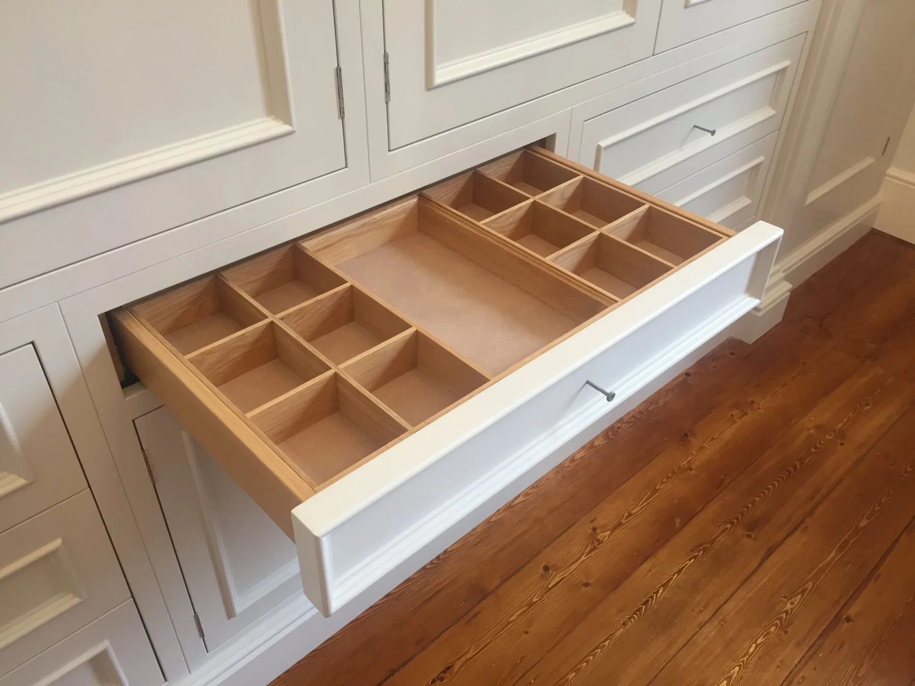 A fitted timber cutlery drawer opened within pale kitchen cabinetry
